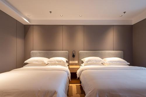 two beds in a hotel room with white sheets at Dayin Garden Hotel -People's Square & Nanjing Road-Large Social Area -Bar -Café -Gym -Free Laundry Luggage Storage -24H Front Desk-English Service in Shanghai
