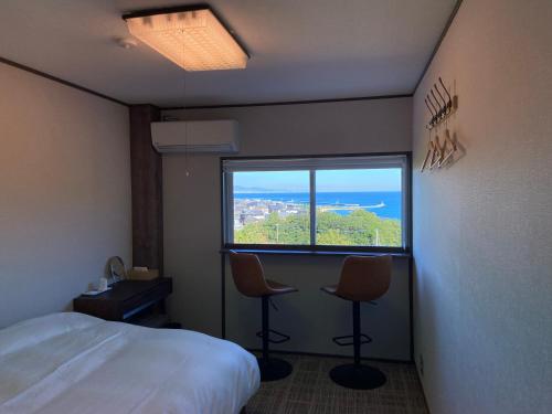a hotel room with a bed and two chairs and a window at Tainan House Awaji in Awaji