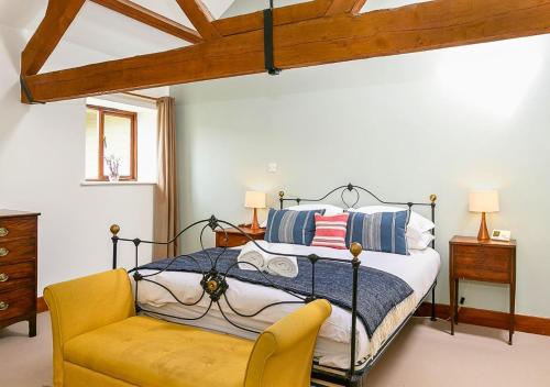 a bedroom with a bed and a yellow chair at Glyme Flat - Peaceful Country Retreat! in Chipping Norton