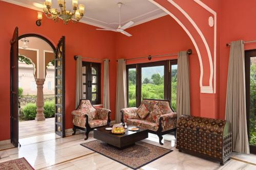 a living room with orange walls and chairs at Shahpura Gandharva Retreat, Sariska in Alwar