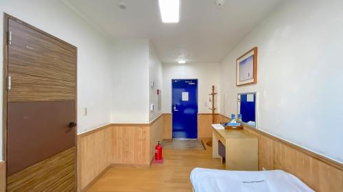 a hospital room with a bed and a blue door at Backpacker's Home in Seogwipo