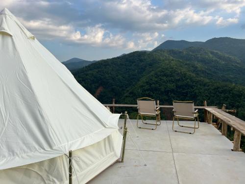 two chairs and a tent on a balcony with mountains at บ้านไร่ไอดอย in Phrae