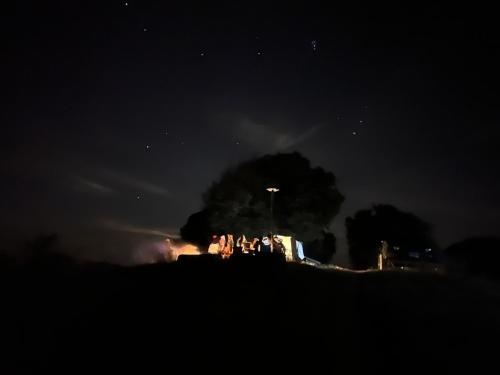 a house on a hill with a fire at night at บ้านไร่ไอดอย in Phrae