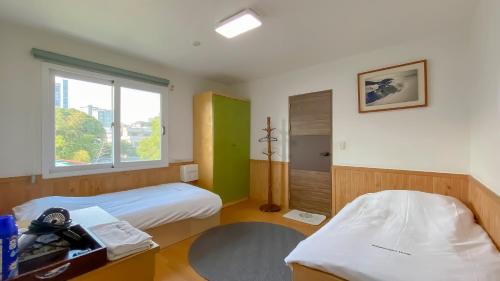 a room with two beds and a window at Backpacker's Home in Seogwipo
