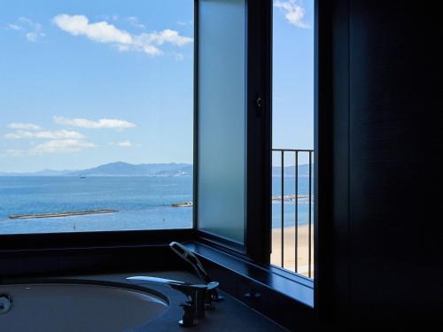a bathroom window with a tub and a view of the ocean at Kobe Suma Seaworld Hotel in Kobe