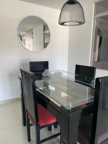 a glass dining table with black chairs and a mirror at Ivanna Jumar ApartaHotel in Medellín