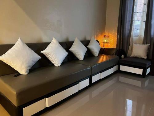 a black couch with white pillows in a living room at Nobieazzir Place in Balintiouac