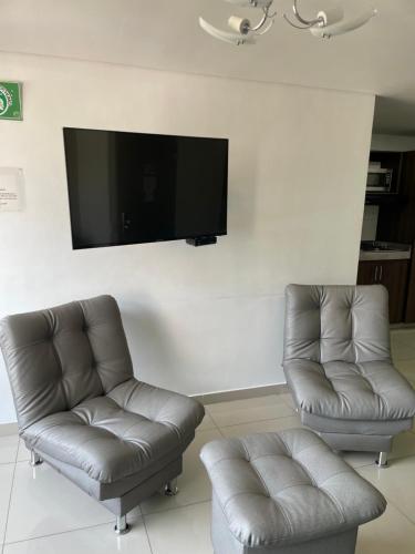 a living room with two chairs and a flat screen tv at Ivanna Jumar ApartaHotel in Medellín