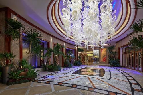 a lobby with a large chandelier and plants at Solaire Resort Entertainment City in Manila