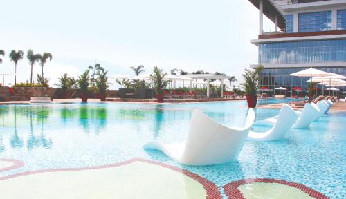 a resort swimming pool with white chairs in the water at Solaire Resort Entertainment City in Manila