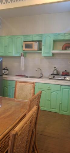 a kitchen with green cabinets and a table with chairs at Tiny house in city proper in Puerto Princesa City