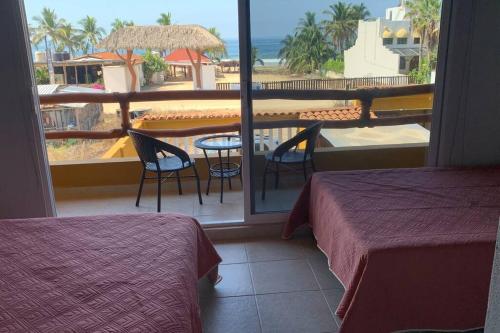 a room with two beds and a balcony with a view of the ocean at Casa Hipocampo a pasos de la playa in Ixtapa-Zihuatanejo International