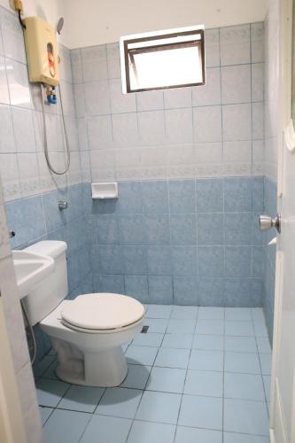 a blue tiled bathroom with a toilet and a window at Island Inn in Boracay