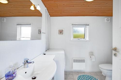 グレーノにあるCozy House Near Grenaa Beach, Close To The Shoreの洗面台とトイレを備えた白いバスルーム