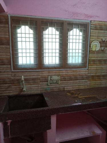 Una cocina con fregadero y dos ventanas. en Sri arunachala shiva homestay 2, en Tiruvannāmalai