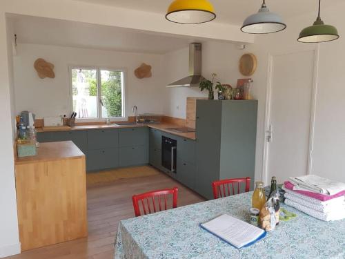 une cuisine avec une table, des chaises rouges et un comptoir dans l'établissement Maison proche mer, à Lancieux