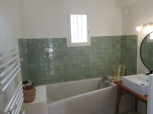 une salle de bain avec une baignoire, un lavabo et un miroir dans l'établissement Maison proche mer, à Lancieux