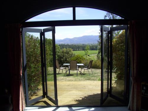 an open door to a patio with a table outside at Omaka Heights Countrystay in Renwick