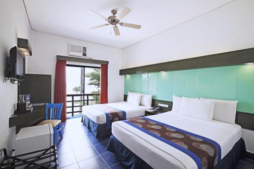a hotel room with two beds and a window at Microtel by Wyndham Puerto Princesa in Puerto Princesa City