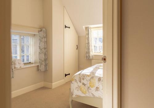 una camera da letto con un letto con specchio e finestre di Jasmine Cottage - 2 Bedroom in Heart of Bourton! a Bourton on the Water