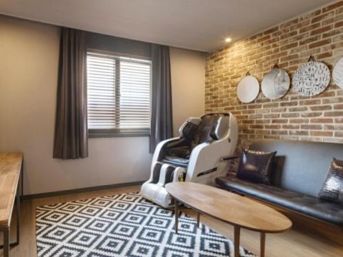 a living room with leather furniture and a brick wall at Hotel Browndot Myeongseo Convention in Changwon