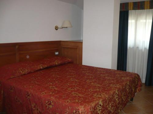 a bedroom with a bed with a red comforter at Hotel Ristorante Antica Marina in Nicotera Marina