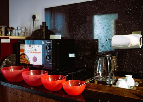 a kitchen with red bowls on a counter with a microwave at Arambol Bliss Hotel Apartments in Arambol