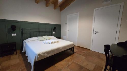 a bedroom with a bed with white sheets and a door at Agriturismo Igino - Camera in Casale con cucina condivisa e spazi comuni, giardino, patio, parcheggio, wineshop, wifi - Immerso nei vigneti in Negrar