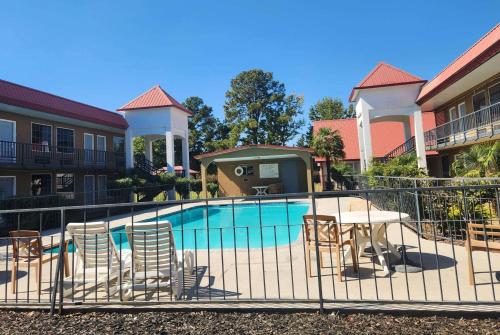 a swimming pool with chairs and a table next to a building at Days Inn by Wyndham Leesville in Leesville
