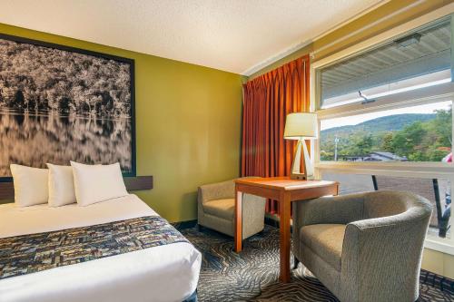 a hotel room with a bed and a chair and a window at Super 8 by Wyndham Lake George/Downtown in Lake George