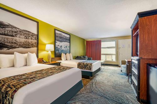 a hotel room with two beds and a flat screen tv at Super 8 by Wyndham Lake George/Downtown in Lake George