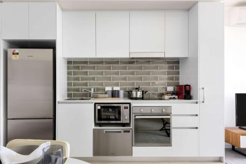 a kitchen with white cabinets and a stove top oven at Ramada by Wyndham VetroBlu Scarborough Beach in Perth
