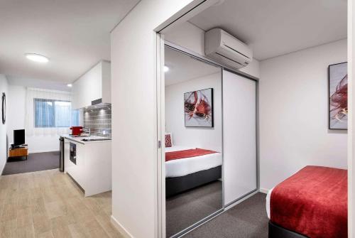 a bedroom with a bed and a mirror in a room at Ramada by Wyndham VetroBlu Scarborough Beach in Perth