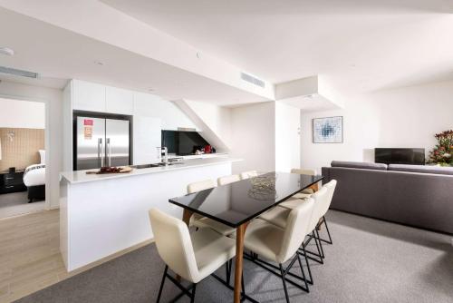 a dining room with a black table and white chairs at Ramada by Wyndham VetroBlu Scarborough Beach in Perth