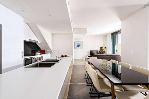 a white kitchen with a long table and chairs at Ramada by Wyndham VetroBlu Scarborough Beach in Perth