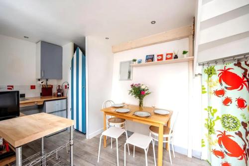 une cuisine et une salle à manger avec une table et des chaises en bois dans l'établissement Charmant appartement à Étretat, 30 m² avec cuisine équipée, à Étretat