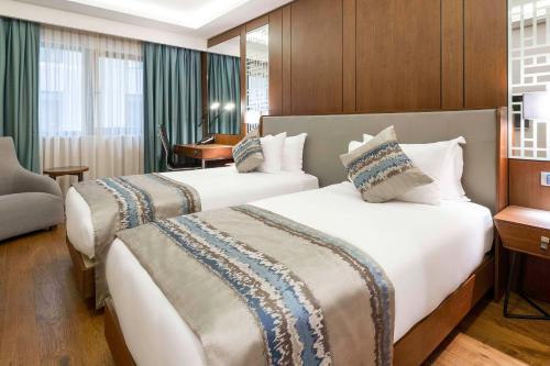 a hotel room with two beds and a desk at Clarion Hotel Golden Horn in Istanbul