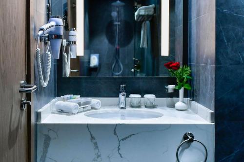a bathroom with a white sink and a mirror at Clarion Hotel Jeddah Airport in Jeddah
