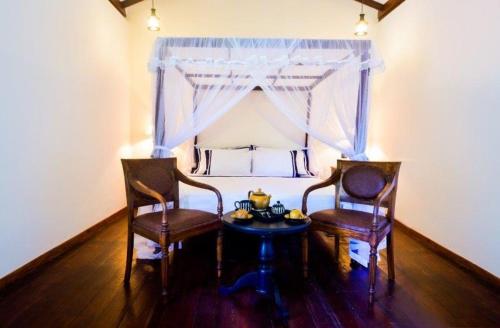 two chairs and a table in a room with a bed at Headman House Antique Villa - Ahangama in Ahangama