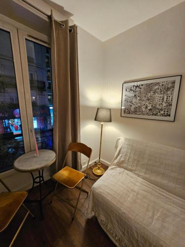 une chambre avec un lit, une table et une fenêtre dans l'établissement Paris Ménilmontant Studio 2 pers, à Paris