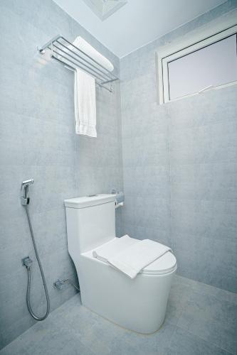 a white bathroom with a toilet and a window at Royal Raj Hotel in Rājshāhi
