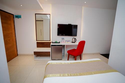 a bedroom with a red chair and a desk with a television at Royal Raj Hotel in Rājshāhi