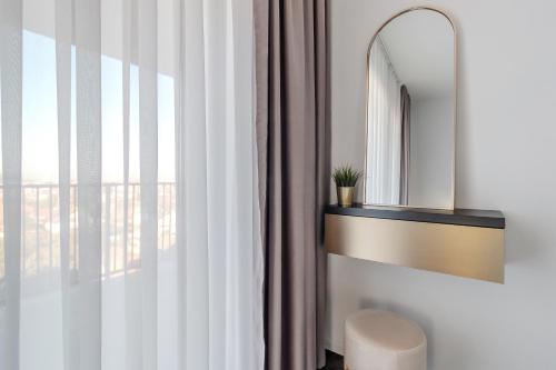 a bathroom with a mirror and a stool next to a window at Sunset Flat in Oradea