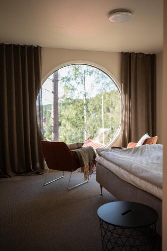 a bedroom with a bed and a chair and a large window at Sjöbodsviken Lövvik in Lövvik