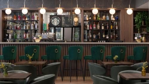 a restaurant with green chairs and a bar at Holiday Inn London Gatwick - Worth by IHG in Crawley