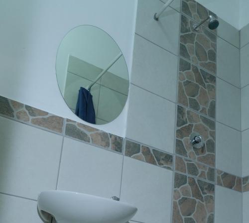 a bathroom with a toilet and a round mirror at SUPA Lodge in Parow