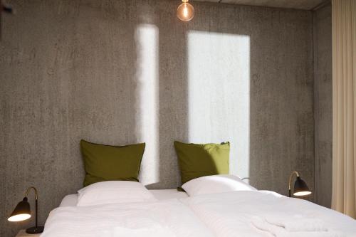 a bedroom with a bed with white sheets and green pillows at Marselisborg Allé 9 B in Aarhus