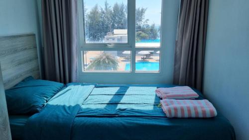 a bed with a window and two pillows on it at Grandblue condominium 405,406 in Ban Tha Fat