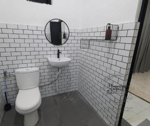a white tiled bathroom with a toilet and a sink at Homestay Pendekar Guntong in Kampong Jereneh