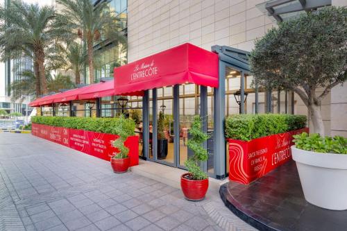 a restaurant with red umbrellas in front of a building at Le Meridien City Center Doha in Doha